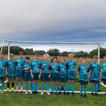 tîm pêl-droed bechgyn yn sefyll o flaen gôl